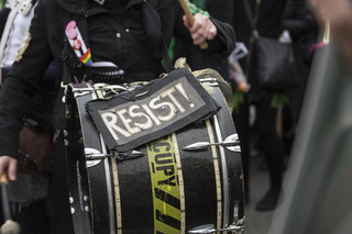 A group of musical performers with instruments play music and lead chants while women march towards the national monument. When asked where they were from, they answered 