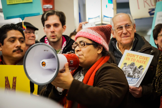 An organizer translates speeches from Spanish to English and starts bilingual chants.