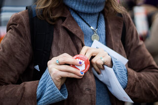 A marcher pins one of Syracuse Graduate Employees United’s (SGEU) pins to their jacket. The organization handed them out for free, along with orange bandanas which sported the same logo. 